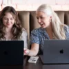 Maddie and Lauren sitting next to each other and discussing someting while looking at their macbooks | Social Media Platforms
