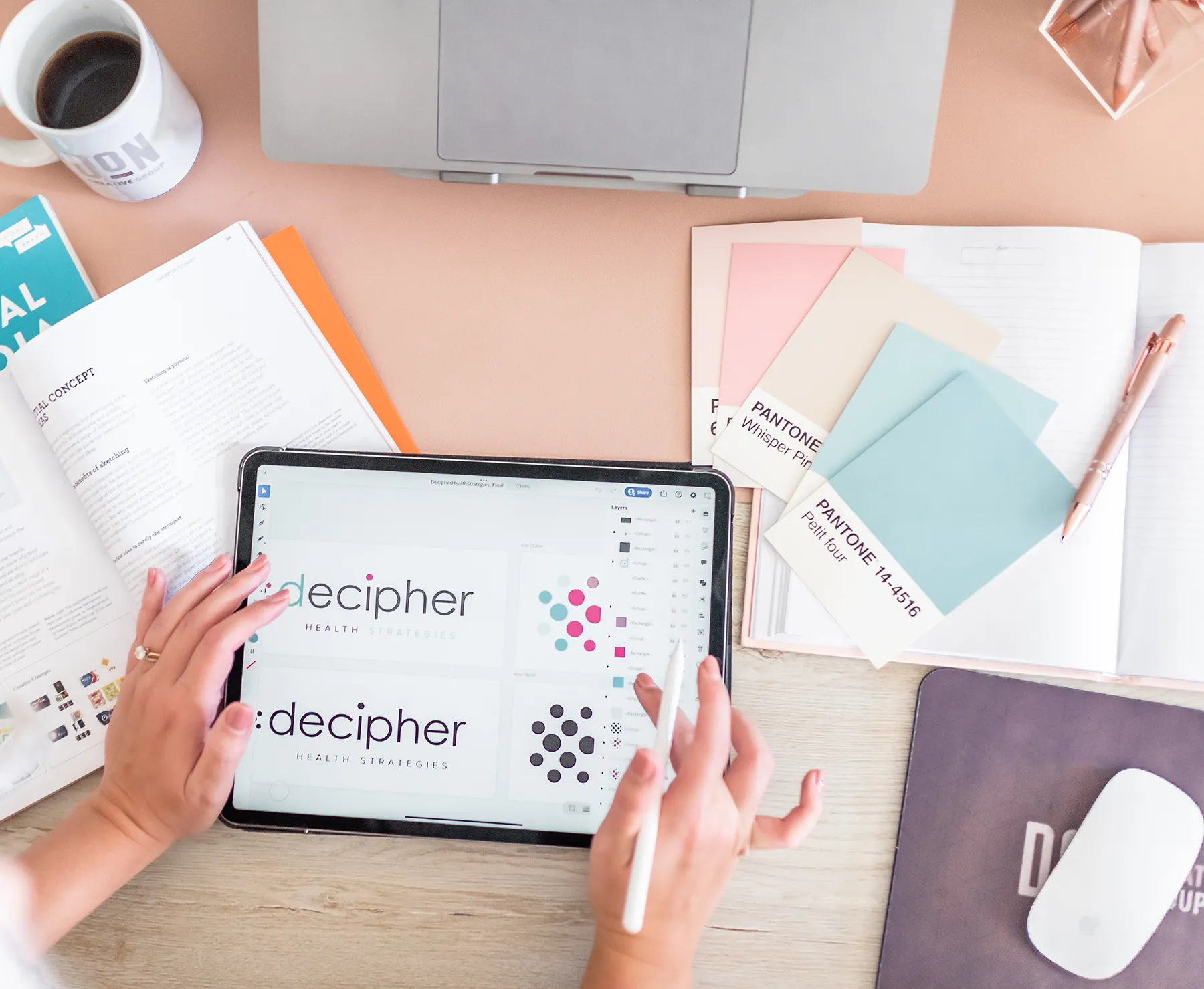 Professional designer at boutique creative agency working on branding and web design project with Pantone color swatches, tablet, and laptop on desk