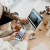 Two people collaborating on digital marketing, reviewing content on a laptop and smartphone.