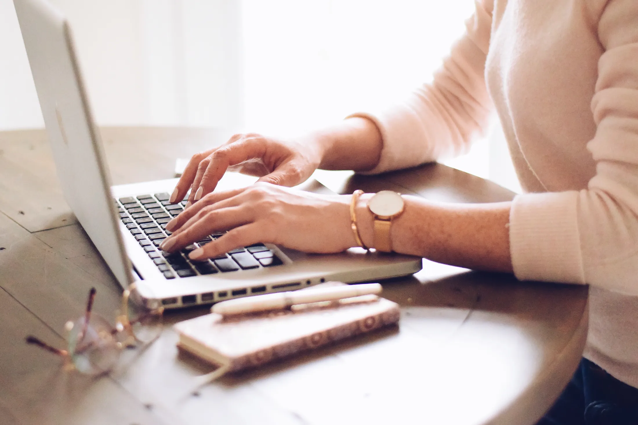 Person typing on a laptop at a desk while writing blog content