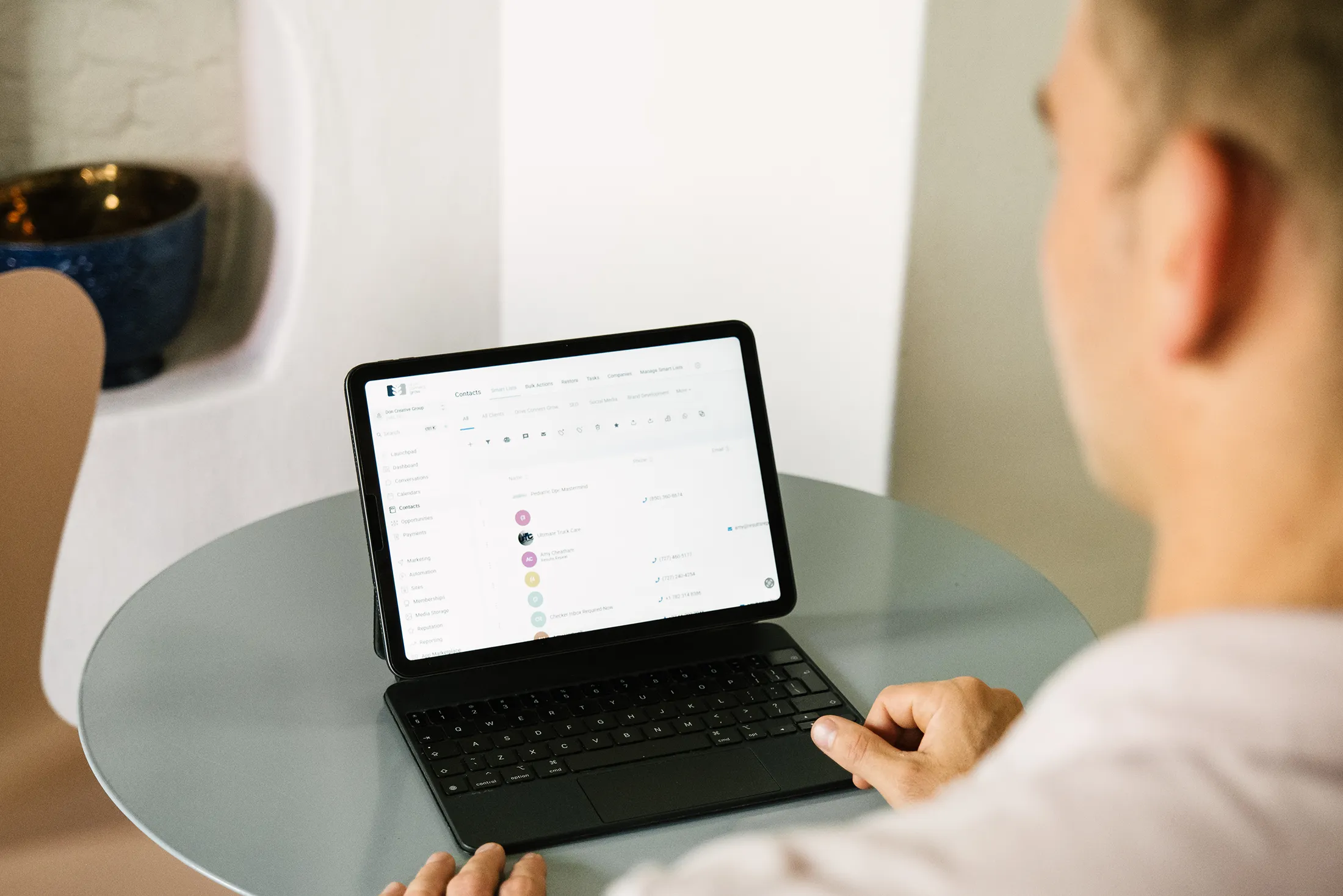 Professional reviewing digital contacts and workflow on a tablet with keyboard at a modern workspace