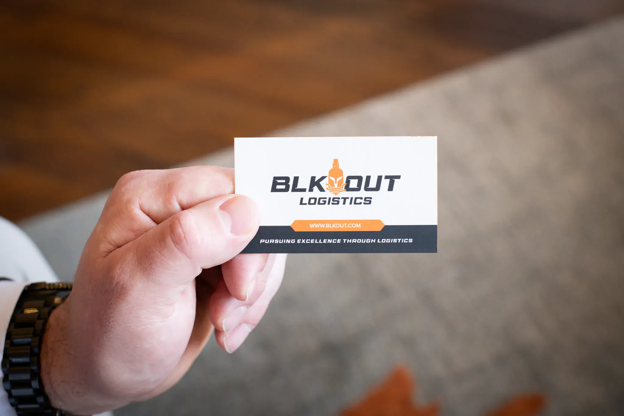 xHand holding BLKOUT Logistics business card with logo and website visible