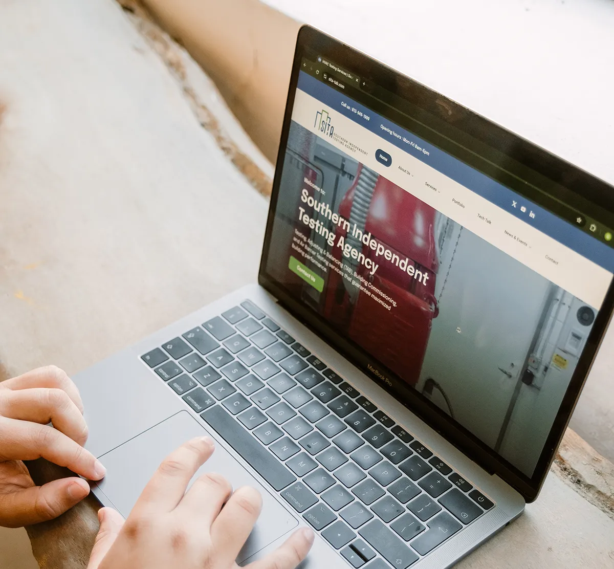 Hands using laptop displaying SITA HVAC testing and commissioning website