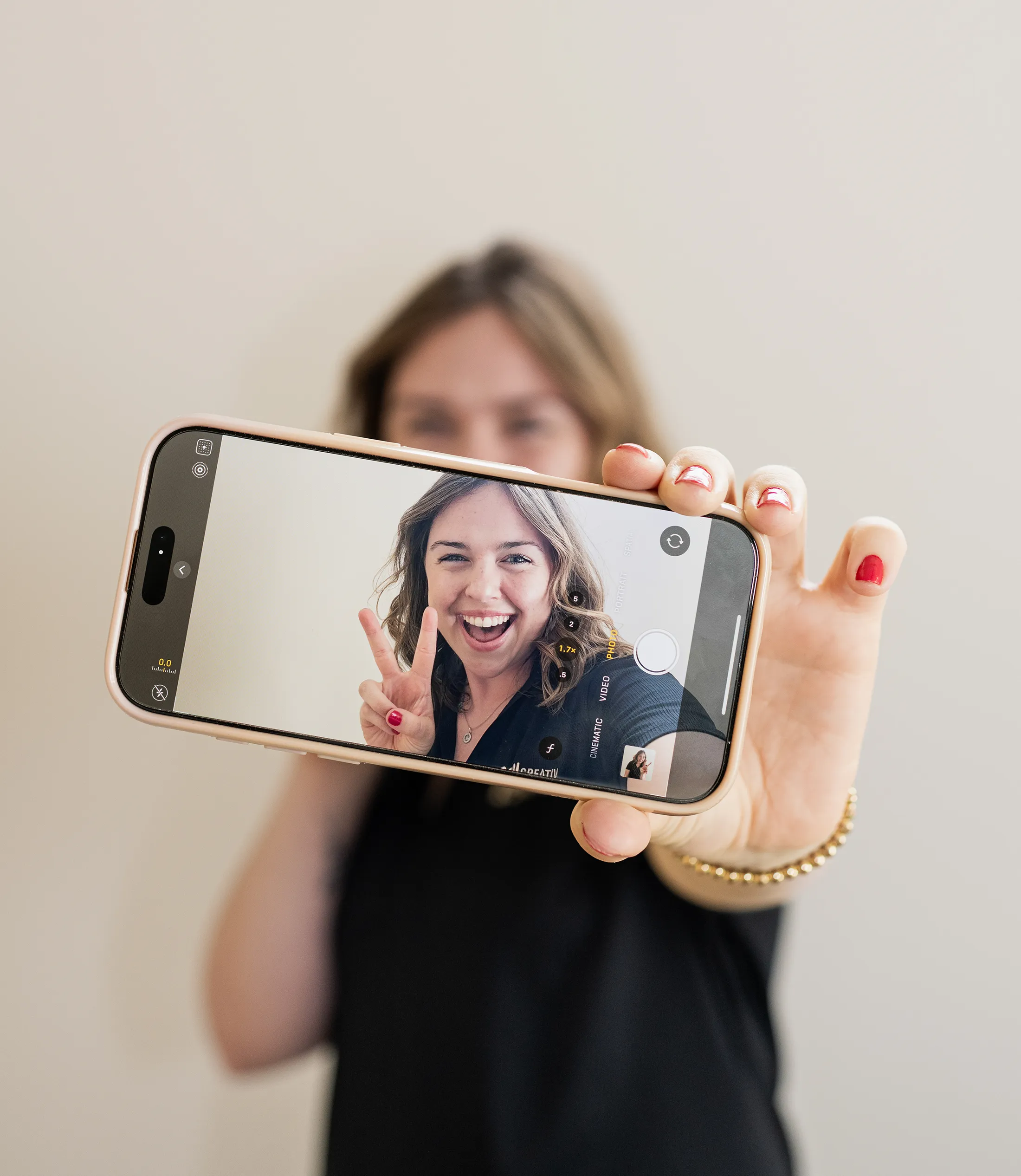 xMaddie holding smartphone toward camera displaying selfie while making peace sign