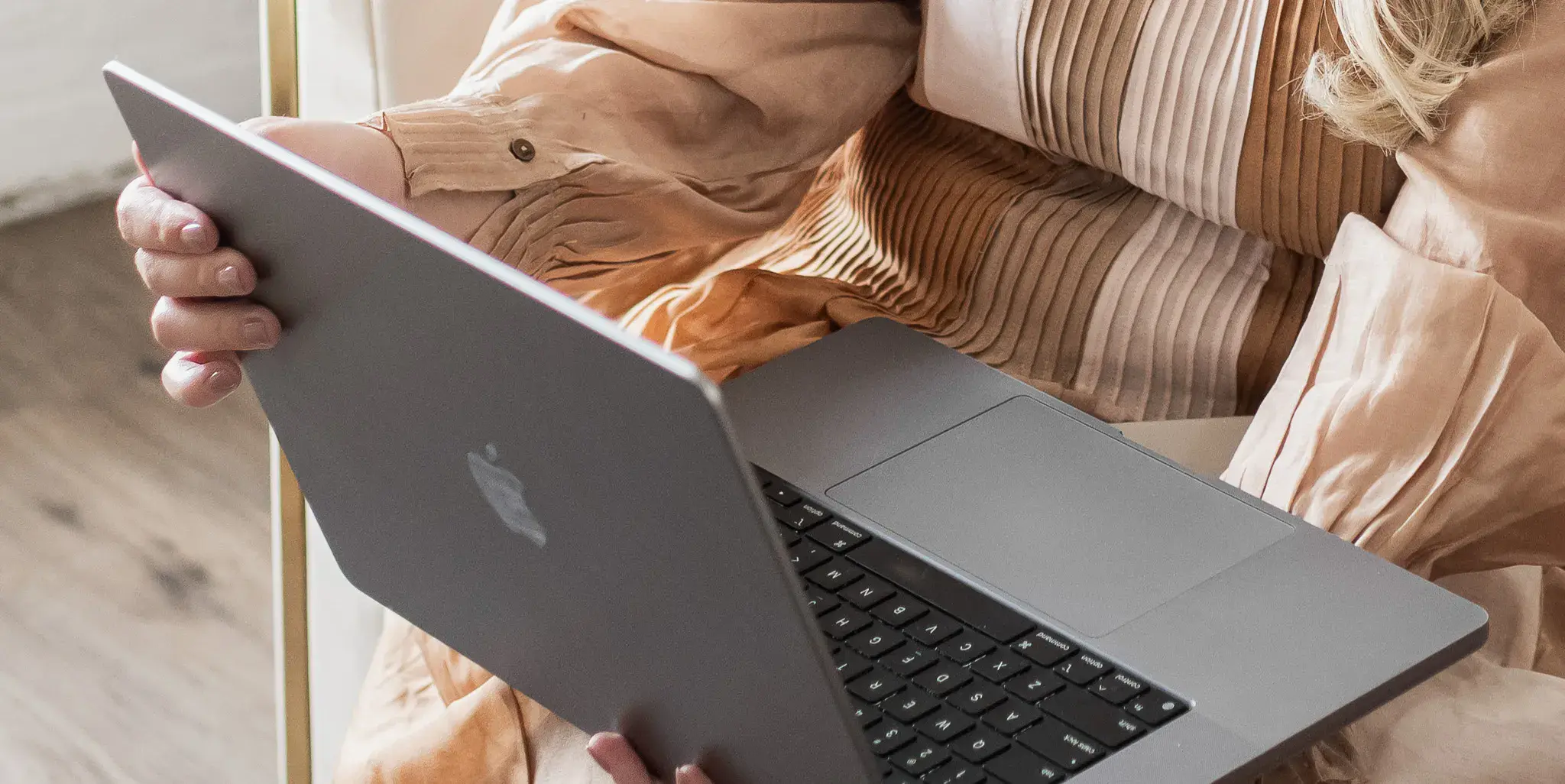 Professional holding open laptop while reviewing content in a seated workspace