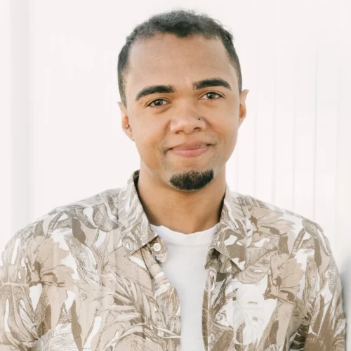 xTeam member facing camera wearing patterned shirt over white t-shirt indoors