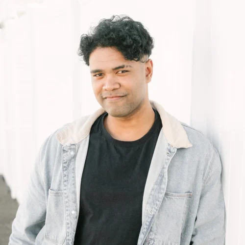 xTeam member wearing black shirt and denim jacket standing against white wall