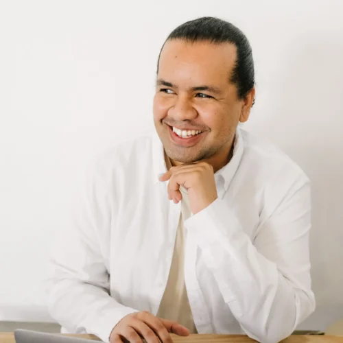 xTeam member in white shirt smiling while seated at desk with laptop