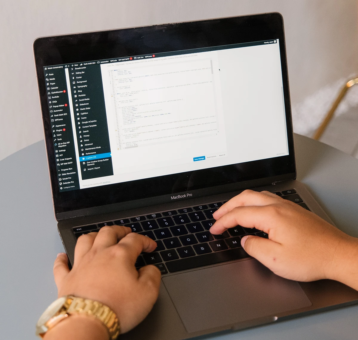 Web developer editing website code on laptop using content management dashboard